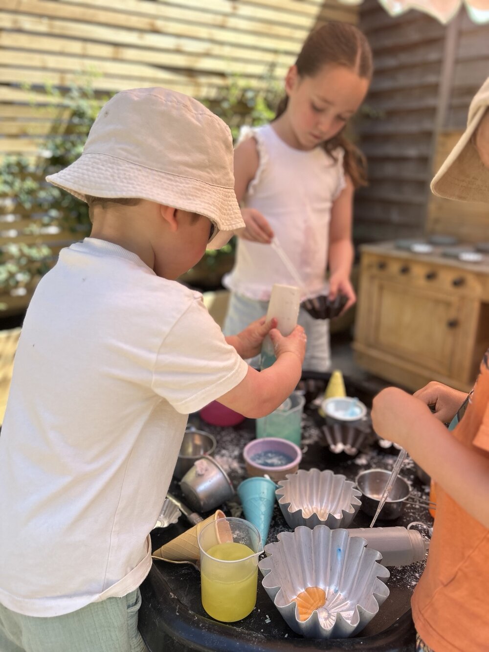 Children exploring cups and containers in a sensory tray